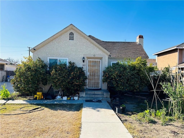 view of front of home featuring a chimney and stucco siding