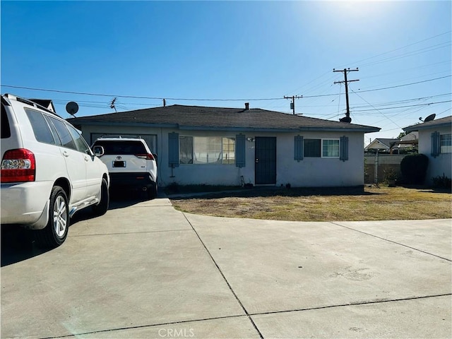 ranch-style home featuring a garage, concrete driveway, and stucco siding