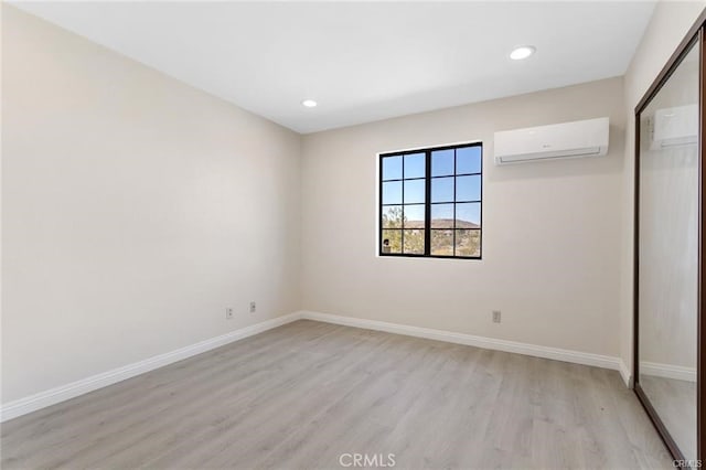 unfurnished bedroom featuring a wall unit AC and light wood-type flooring