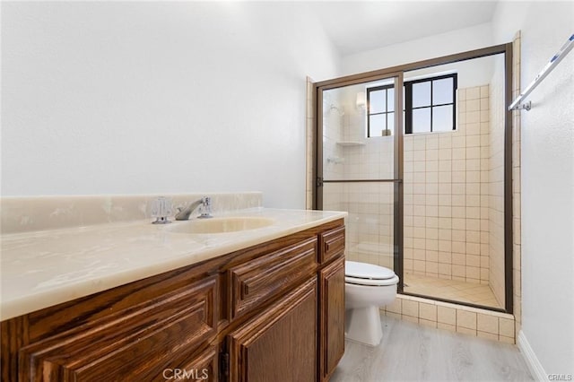 bathroom featuring a shower with shower door, toilet, and vanity