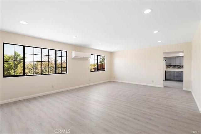 unfurnished room featuring light wood-type flooring and a wall mounted air conditioner