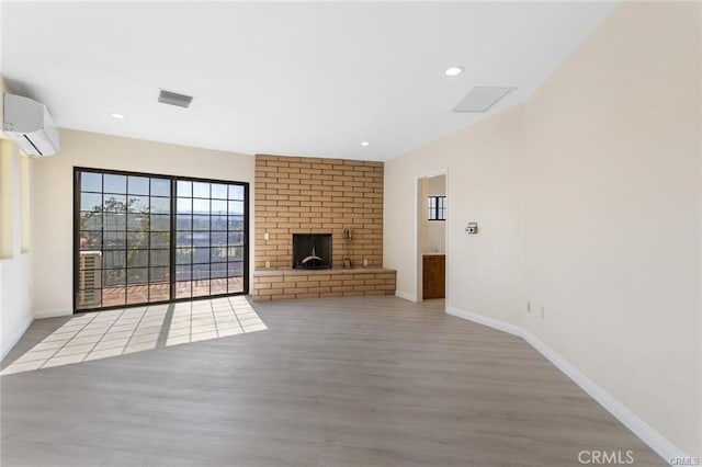 unfurnished living room featuring wood-type flooring, a fireplace, and a wall unit AC