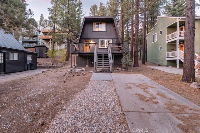 rear view of house featuring stairs and a wooden deck