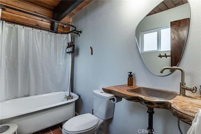 full bathroom with tile patterned floors, toilet, shower / tub combo with curtain, and a sink