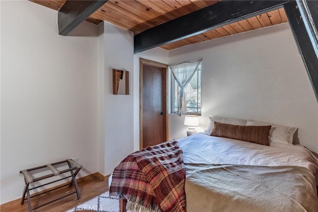 bedroom featuring beamed ceiling, wood-type flooring, and wooden ceiling