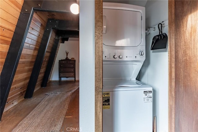 clothes washing area featuring hardwood / wood-style flooring, stacked washer and clothes dryer, and wood walls