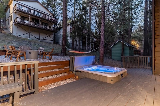 wooden deck featuring a covered hot tub and an outdoor structure