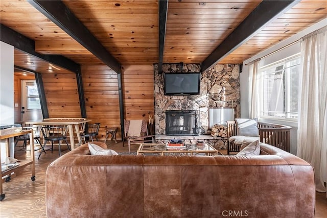 unfurnished living room with a stone fireplace, hardwood / wood-style floors, wood ceiling, and beam ceiling