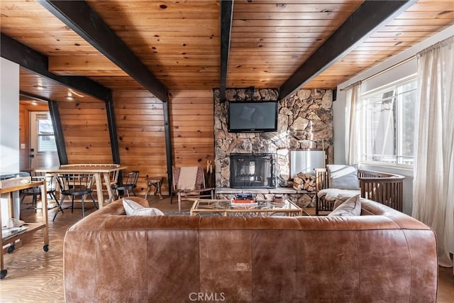 unfurnished living room with a stone fireplace, wooden ceiling, beamed ceiling, and wood finished floors