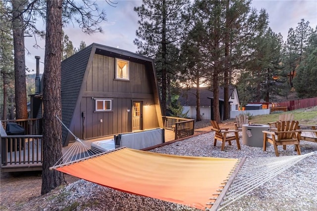 back house at dusk with a wooden deck and a fire pit