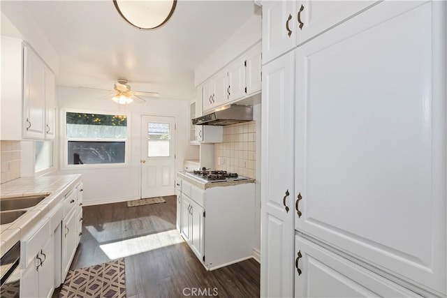 kitchen with stainless steel gas stovetop, white cabinetry, decorative backsplash, tile counters, and ceiling fan