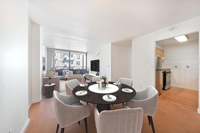 dining space with tile walls and light hardwood / wood-style flooring