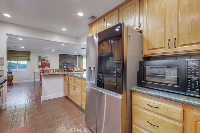 kitchen with light brown cabinetry, a fireplace, and stainless steel fridge with ice dispenser