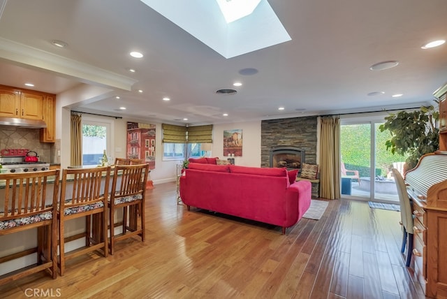 living room with light wood-type flooring, a skylight, a healthy amount of sunlight, and a fireplace