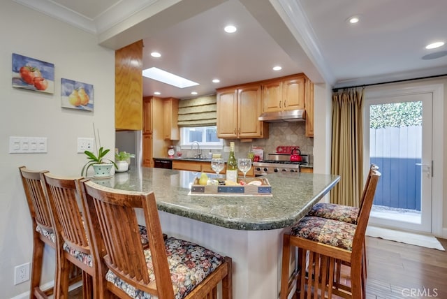 kitchen with wood-type flooring, sink, crown molding, a skylight, and range