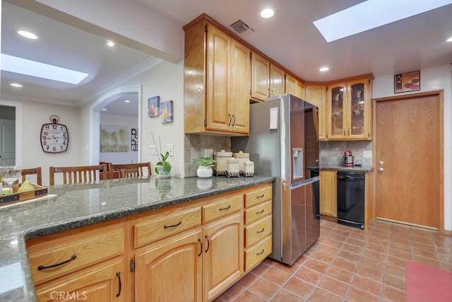 kitchen featuring a skylight, backsplash, and dark stone countertops