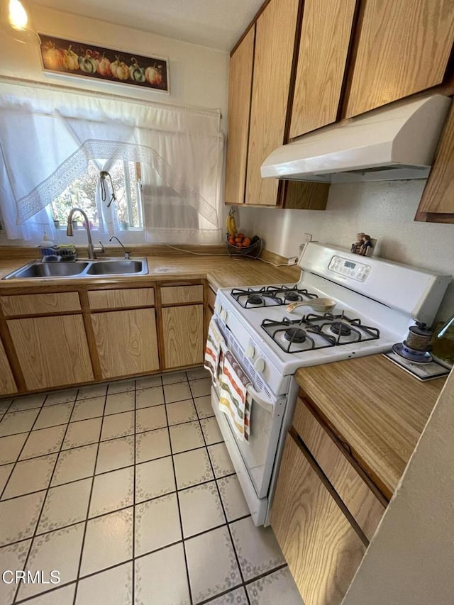 kitchen featuring white range with gas stovetop, sink, and light tile patterned flooring