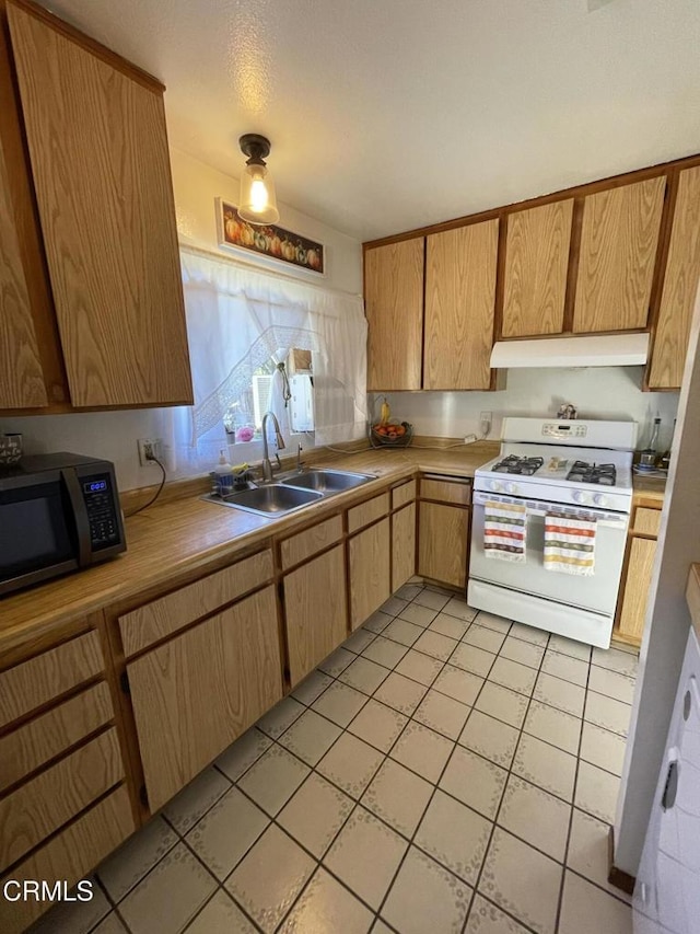 kitchen with white range with gas stovetop, sink, and light tile patterned flooring