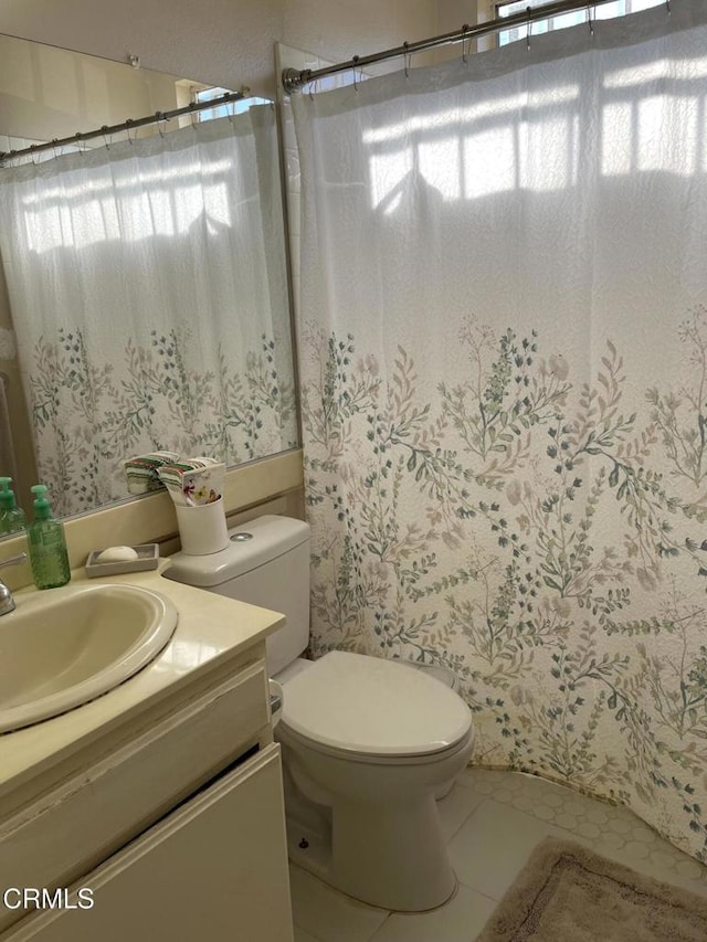 bathroom featuring toilet, a shower with shower curtain, tile patterned floors, and vanity