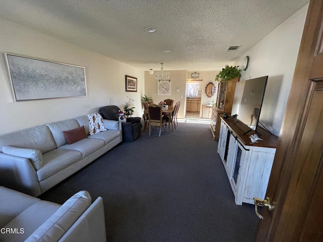 living room with a textured ceiling, a chandelier, and dark colored carpet