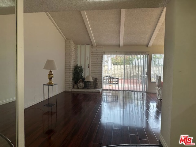 interior space featuring beam ceiling, a textured ceiling, and dark wood-type flooring