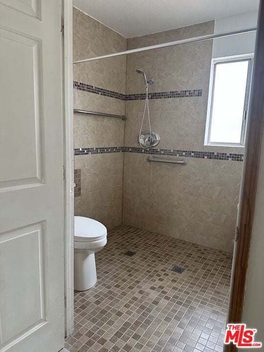 bathroom featuring toilet and tiled shower