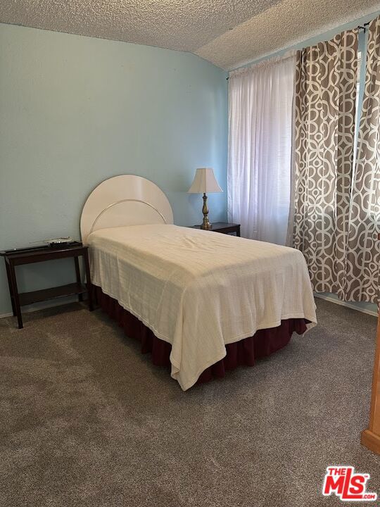 carpeted bedroom with a textured ceiling and lofted ceiling