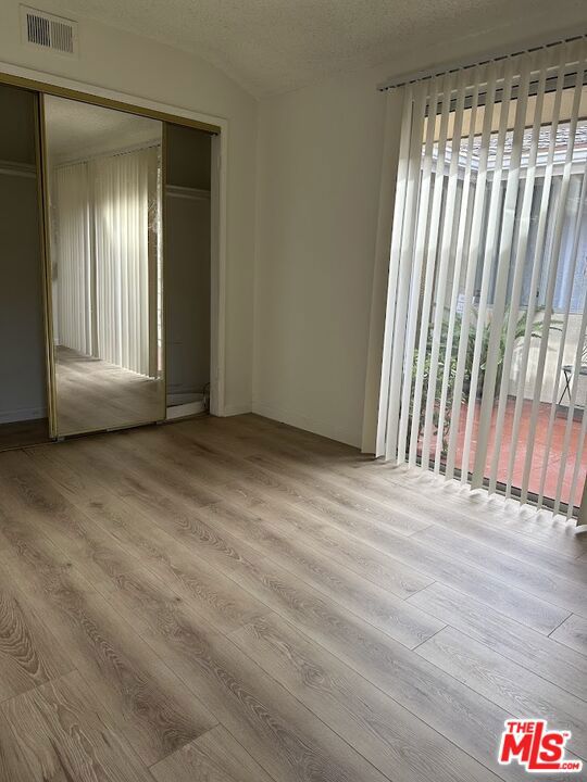 unfurnished bedroom with a closet, light hardwood / wood-style floors, and multiple windows