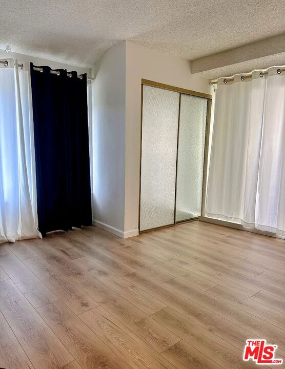 unfurnished bedroom with a closet, a textured ceiling, and light wood-type flooring