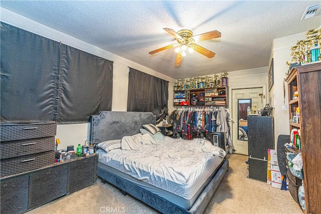 carpeted bedroom featuring ceiling fan and a textured ceiling