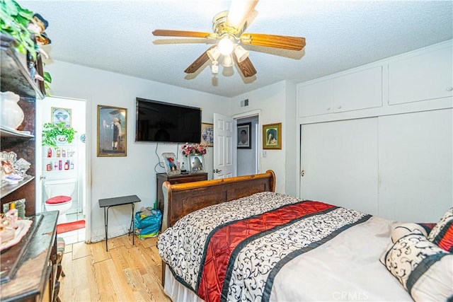 bedroom with ceiling fan, light hardwood / wood-style floors, a textured ceiling, and a closet