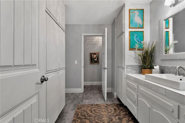 bathroom featuring wood-type flooring, vanity, a textured ceiling, and tasteful backsplash