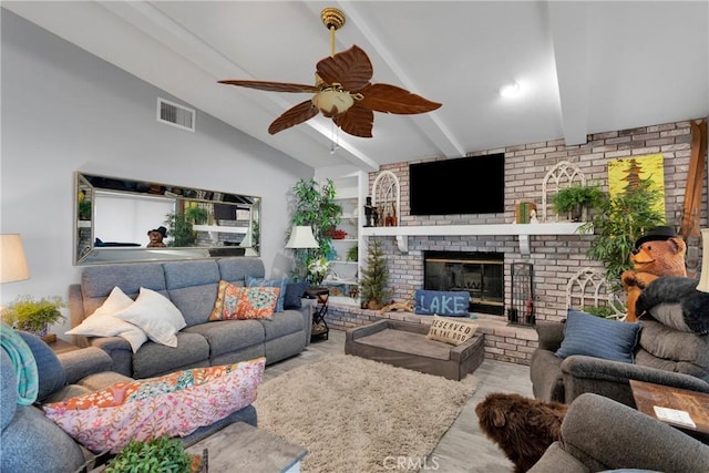 living room featuring ceiling fan, lofted ceiling with beams, a fireplace, and light wood-type flooring