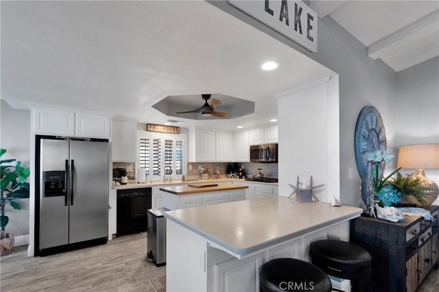 kitchen featuring white cabinetry, ceiling fan, stainless steel appliances, a breakfast bar area, and tasteful backsplash