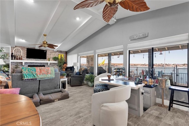 living room with a fireplace, light hardwood / wood-style floors, a water view, and vaulted ceiling with beams