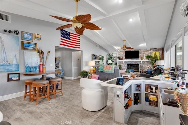 kitchen with a brick fireplace, sink, vaulted ceiling with beams, and ceiling fan