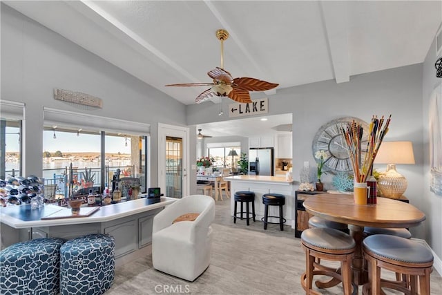 living room with ceiling fan, vaulted ceiling with beams, a healthy amount of sunlight, and light hardwood / wood-style floors