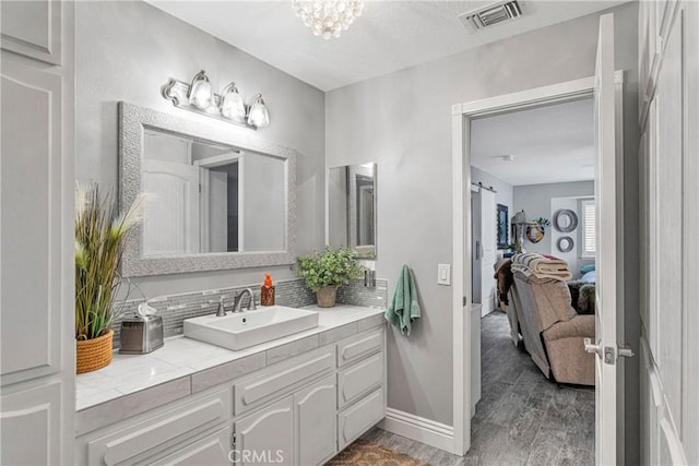 bathroom featuring vanity, decorative backsplash, a chandelier, and wood-type flooring