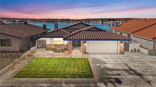 view of front of property featuring a water view, a yard, and a garage