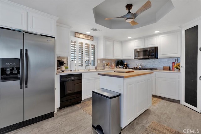 kitchen with ceiling fan, stainless steel appliances, a raised ceiling, white cabinets, and sink