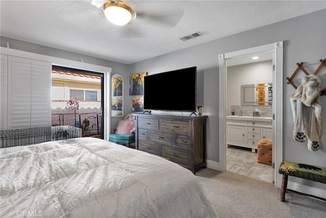 bedroom featuring light carpet, ceiling fan, a textured ceiling, and connected bathroom