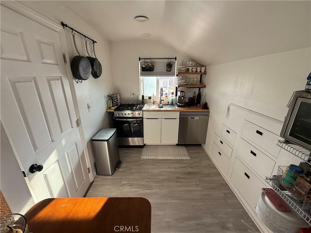 kitchen featuring lofted ceiling, wood-type flooring, appliances with stainless steel finishes, and white cabinetry