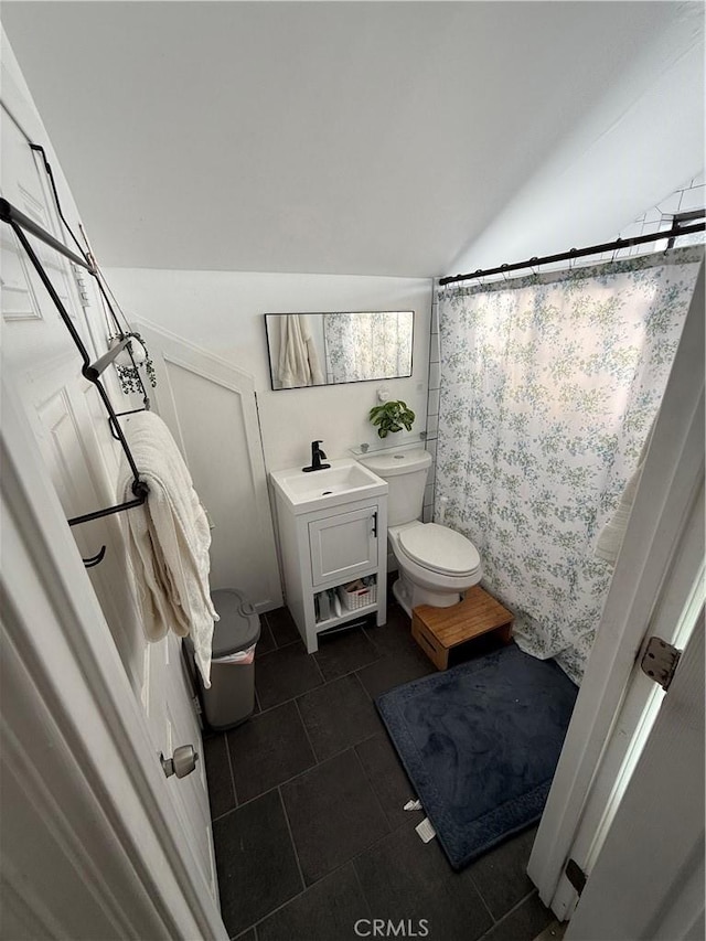 bathroom with toilet, tile patterned flooring, vaulted ceiling, vanity, and curtained shower