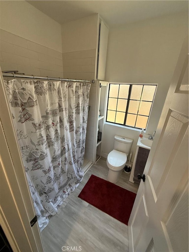 bathroom featuring toilet, a shower with shower curtain, hardwood / wood-style flooring, and vanity