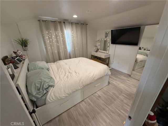 bedroom featuring light wood-type flooring and vaulted ceiling