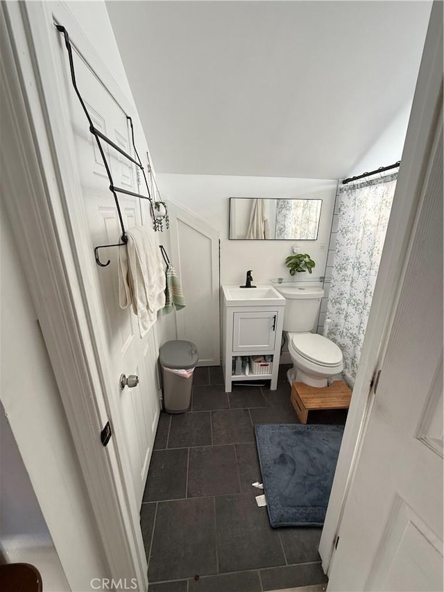 bathroom featuring tile patterned floors, sink, toilet, walk in shower, and vaulted ceiling