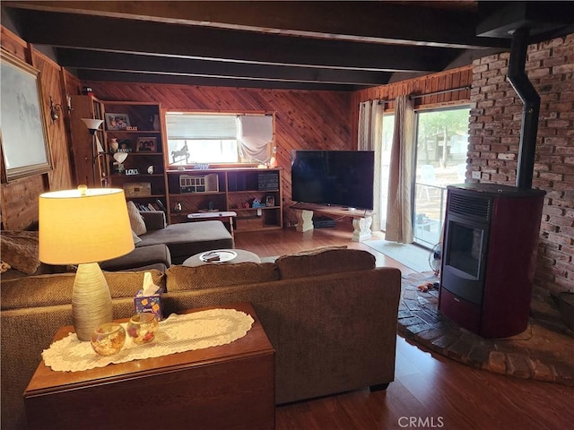 living room with a wood stove, plenty of natural light, beamed ceiling, and wooden walls