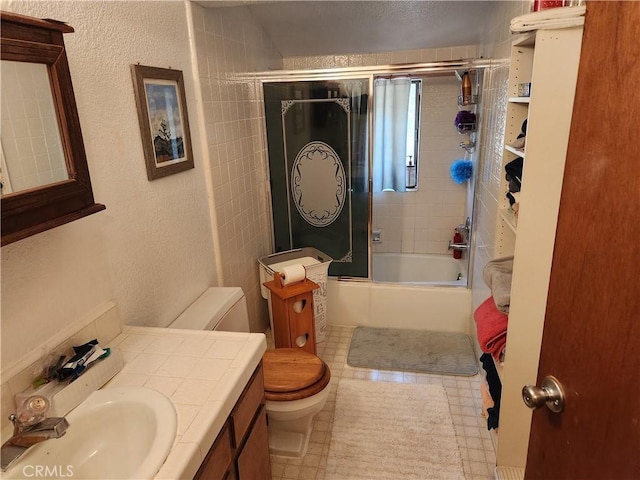 full bathroom with bath / shower combo with glass door, toilet, and vanity