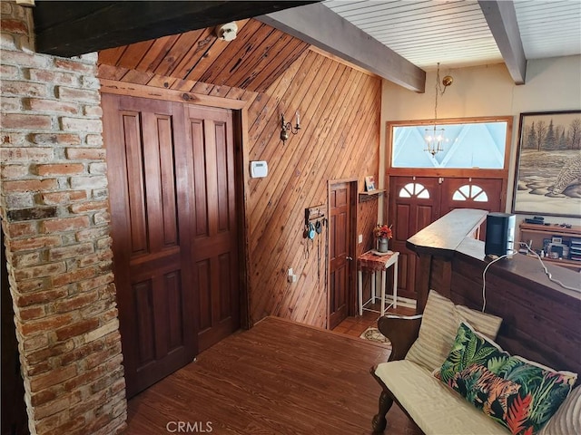 entryway with wood walls, hardwood / wood-style floors, beam ceiling, and a notable chandelier