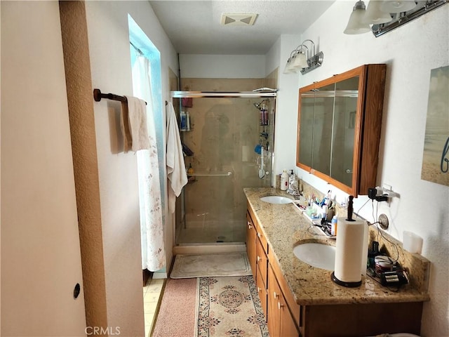 bathroom featuring a shower with shower door, vanity, and tile patterned floors